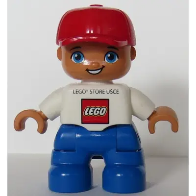 Duplo Figure Lego Ville, Child Boy, Blue Legs, White Top, Red Cap LEGO Logo and 'LEGO STORE UŠCE' on Front